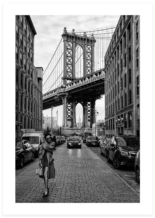 svartvit poster av en kvinna som går framför broklyn bridge i en gata av bilar av robert bolton
